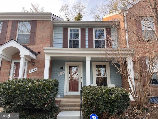 view of property with brick siding and covered porch