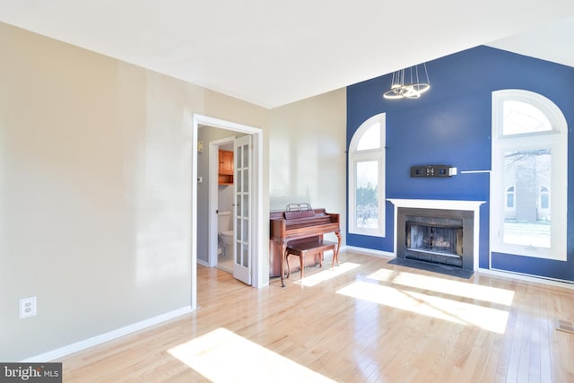 living room featuring wood finished floors, a fireplace with flush hearth, and baseboards