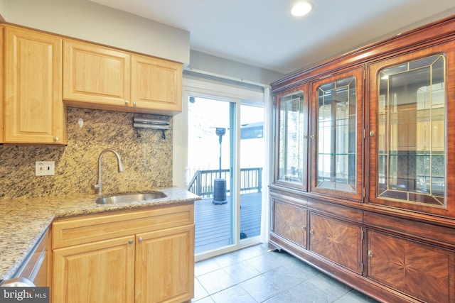 kitchen featuring tasteful backsplash, light brown cabinets, a sink, and light stone countertops