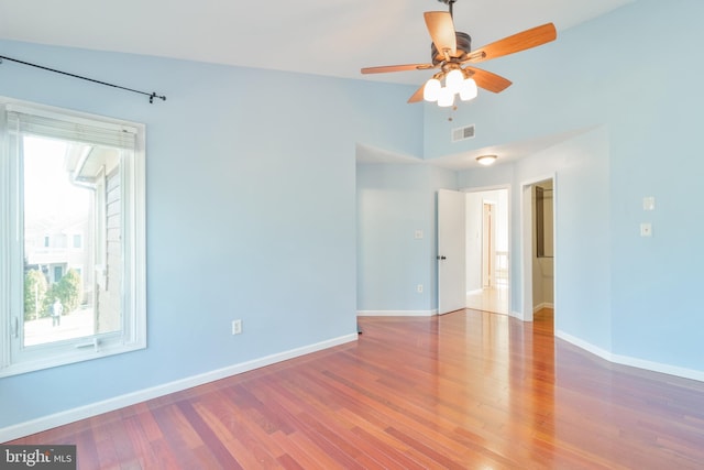 unfurnished room with wood finished floors, a ceiling fan, visible vents, vaulted ceiling, and baseboards