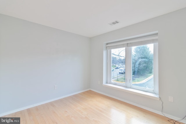 spare room featuring light wood-style floors, visible vents, and baseboards