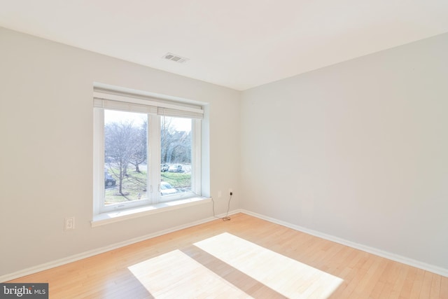 empty room with light wood finished floors, baseboards, and visible vents