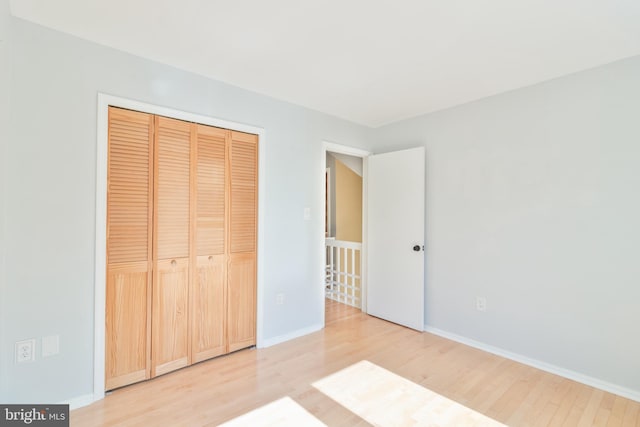 unfurnished bedroom featuring light wood finished floors, a closet, and baseboards