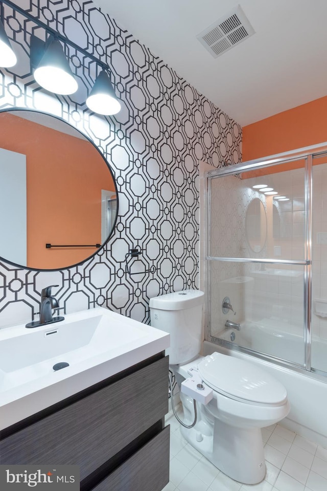 bathroom featuring toilet, bath / shower combo with glass door, vanity, visible vents, and wallpapered walls