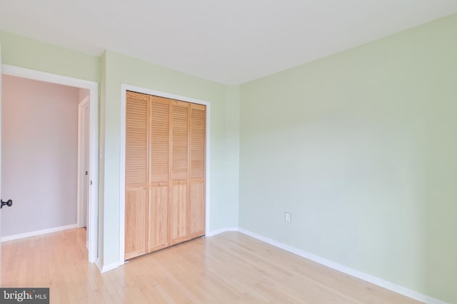 unfurnished bedroom with light wood finished floors, baseboards, and a closet