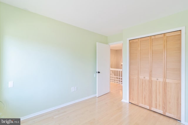 unfurnished bedroom featuring light wood-type flooring, a closet, and baseboards