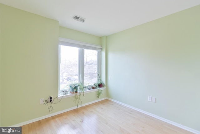 empty room with baseboards, visible vents, and wood finished floors