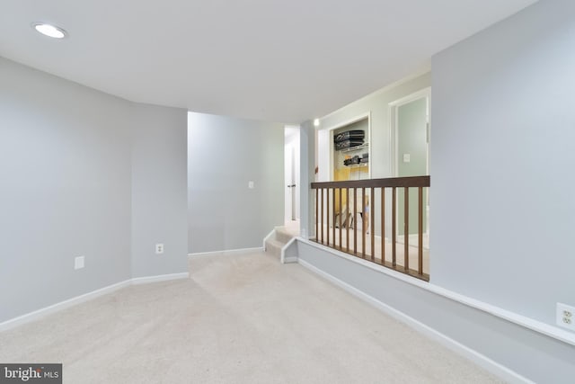 carpeted empty room with stairs and baseboards