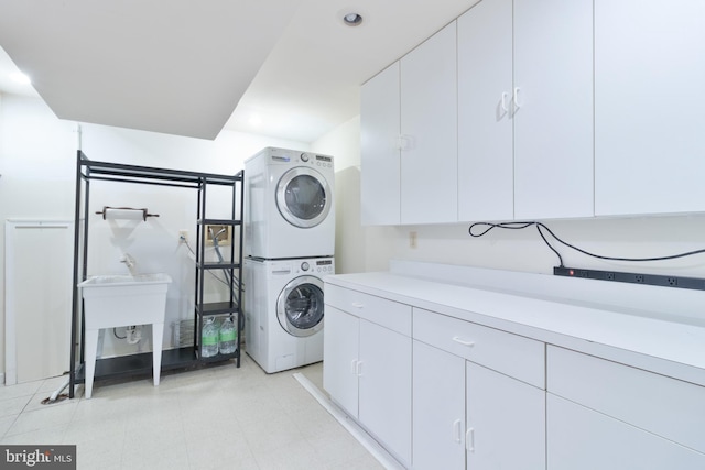 laundry room featuring cabinet space and stacked washer and clothes dryer