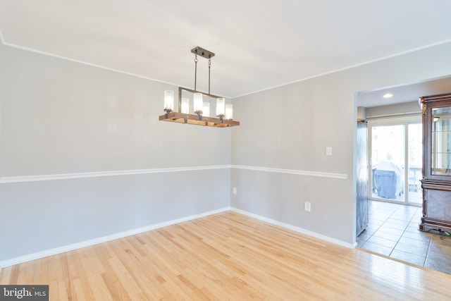 spare room with baseboards and wood finished floors