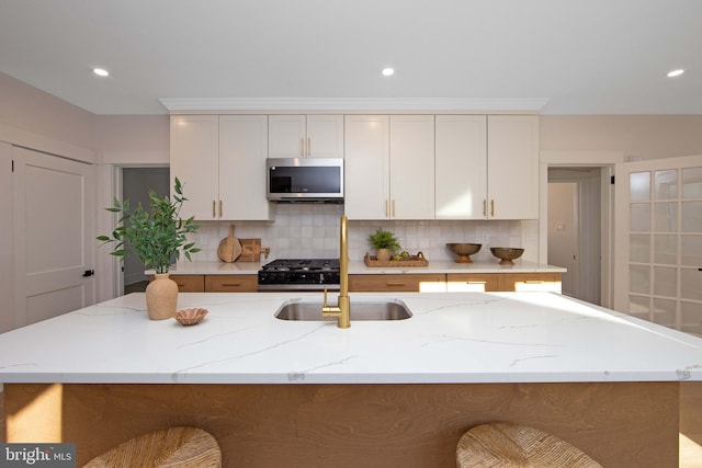 kitchen with tasteful backsplash, stainless steel microwave, range, and light stone counters