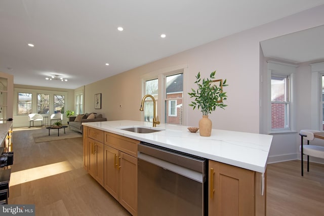 kitchen featuring a sink, open floor plan, light wood-type flooring, dishwasher, and an island with sink