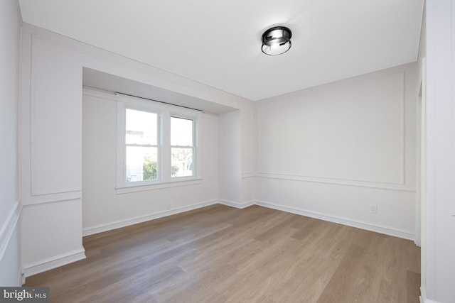 spare room with baseboards and light wood finished floors