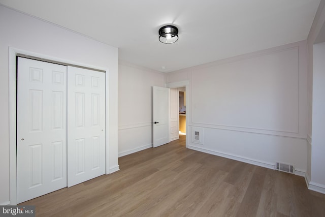 unfurnished bedroom with a closet, visible vents, baseboards, and light wood finished floors