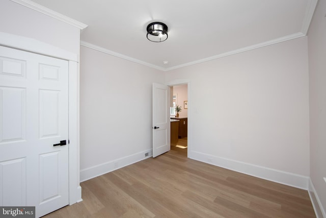 unfurnished bedroom featuring light wood-style floors, baseboards, ornamental molding, and a closet