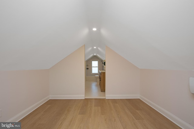 bonus room with light wood-style flooring, baseboards, and vaulted ceiling