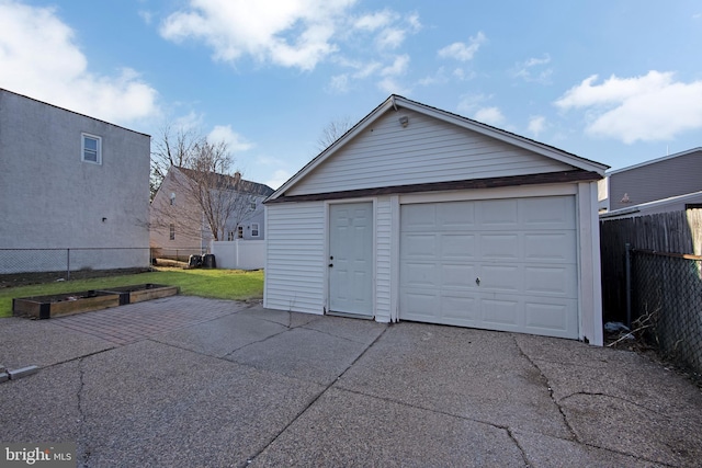 detached garage with a garden, fence, and driveway