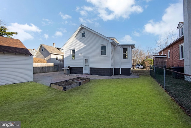 rear view of house featuring a patio, a fenced backyard, a vegetable garden, and a lawn