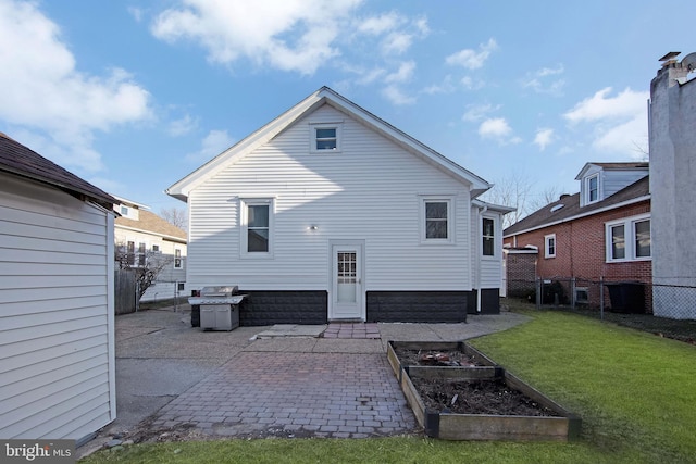 rear view of house with a patio area, a garden, a lawn, and fence