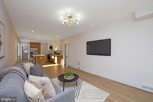 living area with baseboards, visible vents, an inviting chandelier, light wood-style floors, and recessed lighting