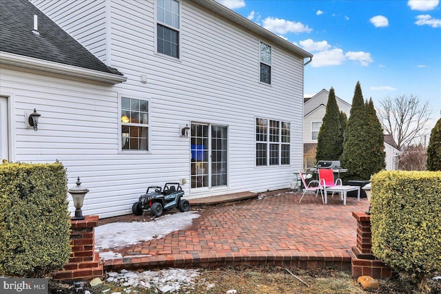 rear view of property featuring a shingled roof and a patio