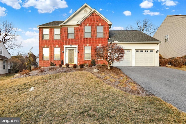 colonial home featuring aphalt driveway, a front yard, brick siding, and an attached garage