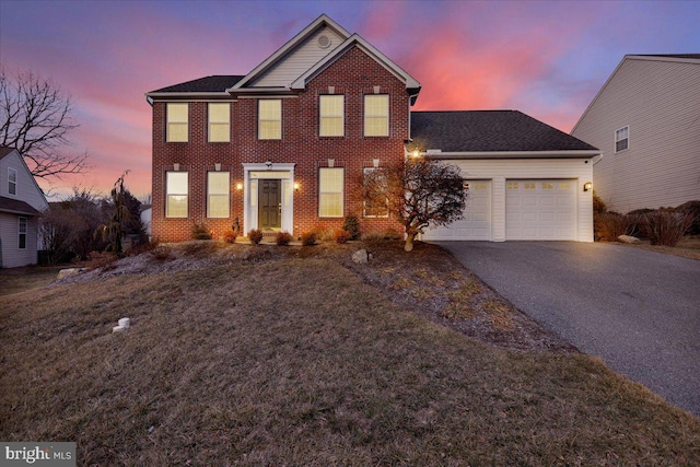 view of front of home with driveway, an attached garage, and brick siding