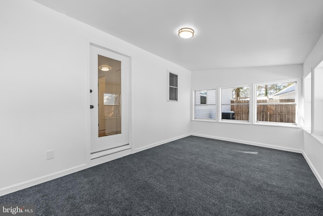 unfurnished room with dark carpet and baseboards