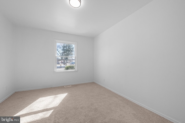 carpeted spare room featuring baseboards