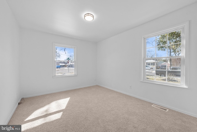 carpeted spare room featuring baseboards and visible vents