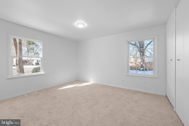 unfurnished bedroom featuring baseboards, visible vents, and light colored carpet