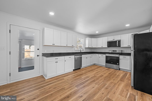 kitchen with recessed lighting, white cabinetry, light wood-style floors, appliances with stainless steel finishes, and dark countertops