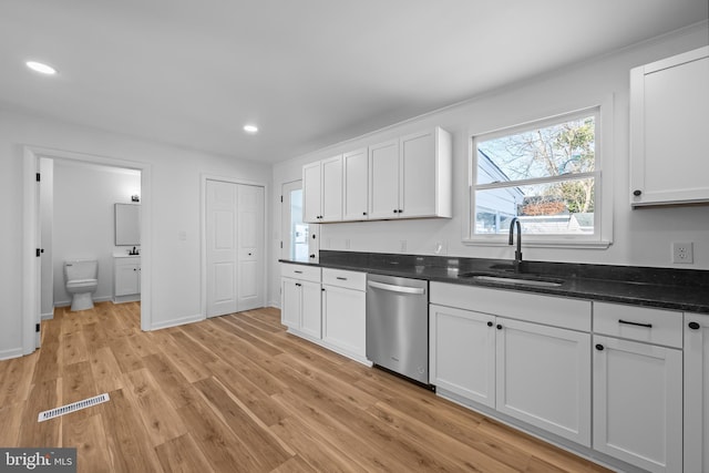 kitchen with a sink, light wood-style flooring, white cabinets, and dishwasher