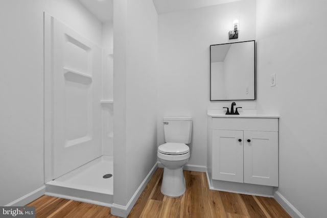 bathroom with toilet, a shower stall, baseboards, and wood finished floors