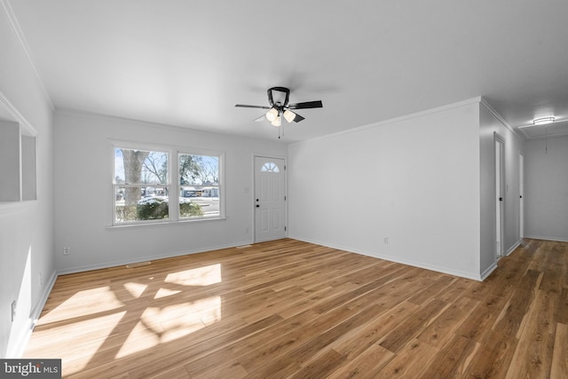 interior space with attic access, ceiling fan, ornamental molding, and wood finished floors