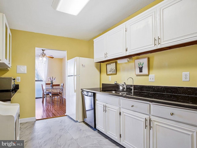 kitchen with a sink, white cabinets, marble finish floor, stainless steel dishwasher, and dark stone counters