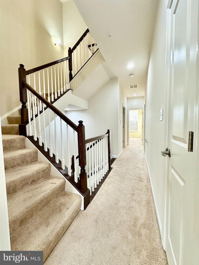 staircase featuring baseboards, visible vents, and carpet flooring