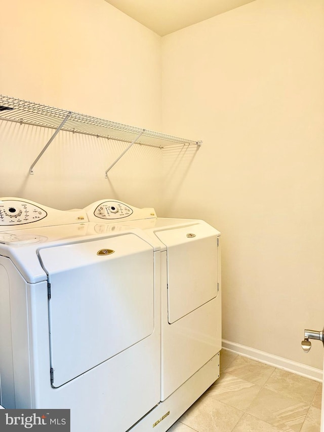 clothes washing area with laundry area, washing machine and clothes dryer, and baseboards