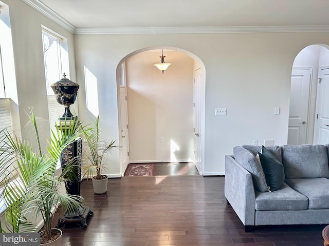 entrance foyer with arched walkways, ornamental molding, and dark wood finished floors