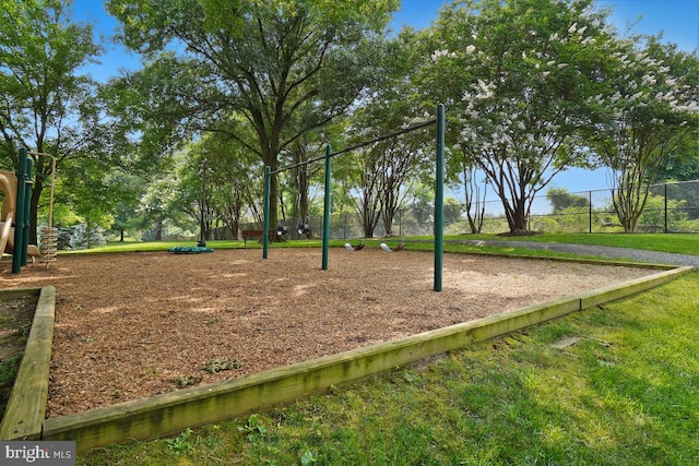 view of community featuring fence, playground community, and a yard