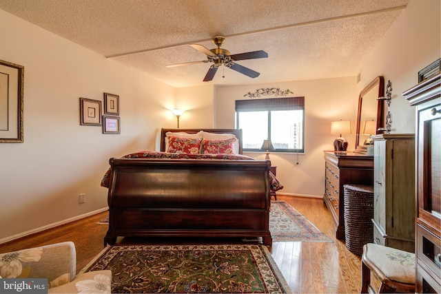 bedroom with a textured ceiling, baseboards, and wood finished floors