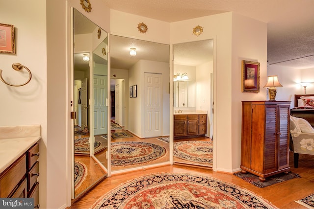 bathroom with a textured ceiling, baseboards, wood finished floors, and vanity