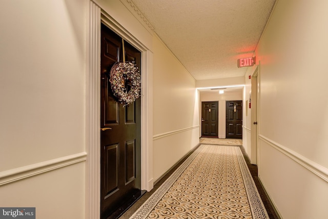 hall with baseboards and a textured ceiling