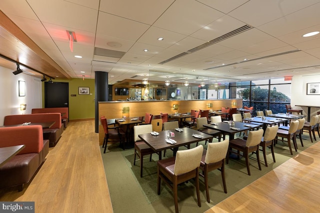 dining space with wood finished floors, a paneled ceiling, and baseboards