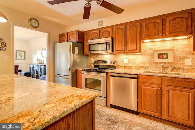 kitchen featuring brown cabinetry, visible vents, appliances with stainless steel finishes, and decorative backsplash