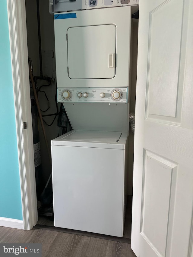 washroom with laundry area, wood finished floors, and stacked washer and clothes dryer