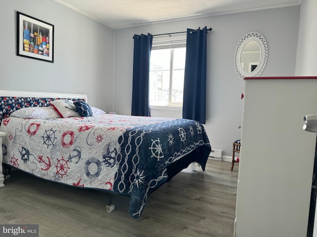 bedroom featuring a textured ceiling, ornamental molding, a baseboard radiator, and wood finished floors