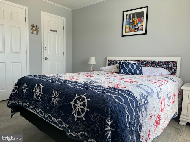 bedroom featuring ornamental molding and wood finished floors