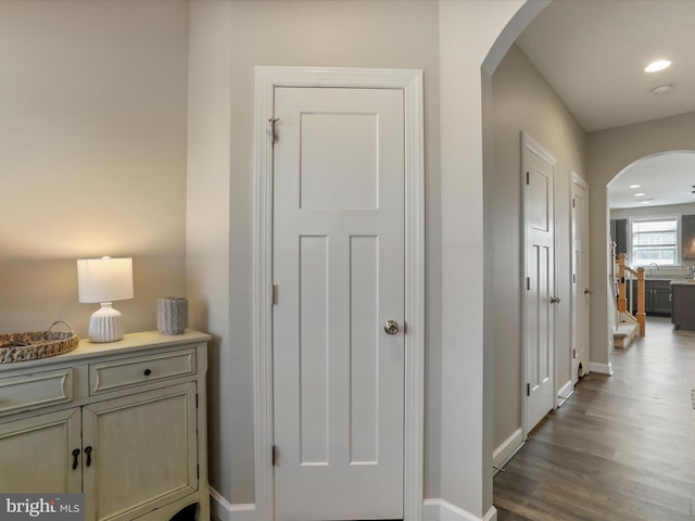 hall featuring arched walkways, recessed lighting, wood finished floors, and baseboards