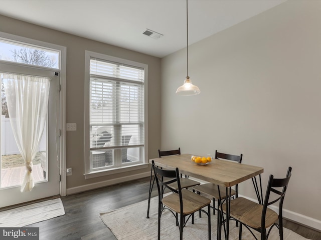 dining area with dark wood-style flooring, visible vents, plenty of natural light, and baseboards